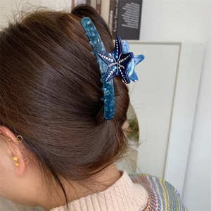Dettaglio di una pinza per capelli a forma di stella marina blu su capelli lunghi