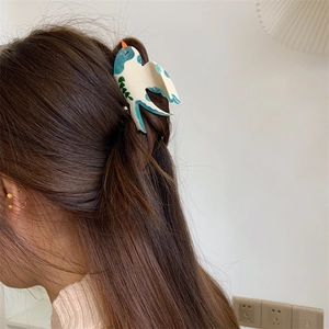 Détail d'une pince à cheveux en forme d'oiseau avec motif marbré bleu sur un mannequin