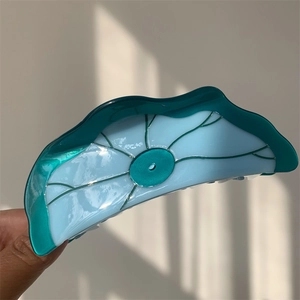 Détail d'une grande pince à cheveux en acétate, design feuille au dégradé bleu