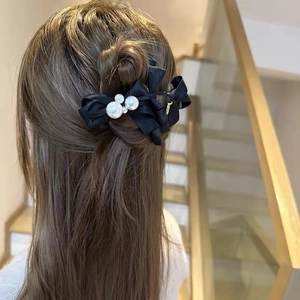Elegant black silk bow hair clip with faux pearls worn on a woman's long hair