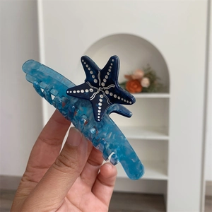 Dettaglio molletta per capelli in acetato blu con stella marina e trama marmorea