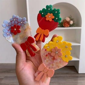 Dettaglio di fermagli per capelli a fiore in acetato con strass brillanti e fiocchi