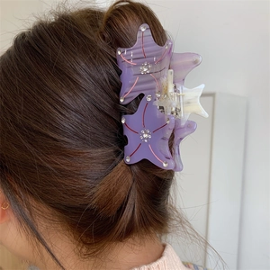 Detailed view of a purple starfish claw clip with rhinestones worn on long hair