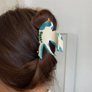 Détail d'une pince à cheveux en acétate en forme d'hirondelle avec motifs de vagues