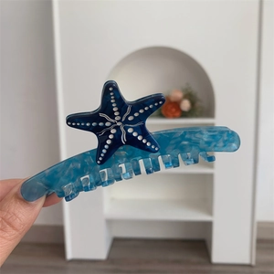 Dettaglio di un fermaglio per capelli a stella marina blu in acetato marmorizzato