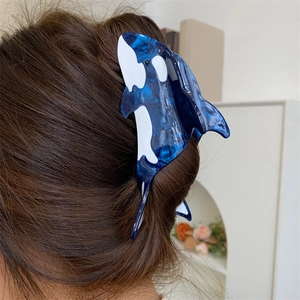 Detailed view of an orca whale hair claw clip with blue marble texture on long brown hair