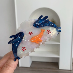 Detailed shot of ocean-themed hair claw clip with dolphin motifs and red rhinestones