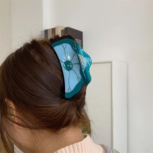 Détail d'une grande pince à cheveux en acétate avec texture de feuille en bleu-vert translucide