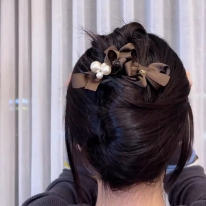 Detail view of coffee brown ribbon bow hair clip with white pearls on wavy hair