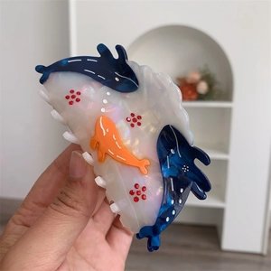Detailed view of ocean-themed acetate hair claw featuring blue whales and red floral rhinestones