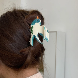 Gros plan d'une pince à cheveux hirondelle en acétate avec motifs à l'encre bleue