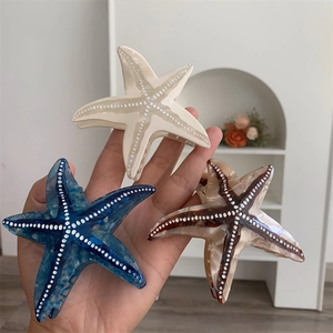 Détail de pinces à cheveux étoile de mer en acétate marbré crème, bleu et ambré