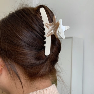 Dettaglio del fermaglio per capelli a stella marina in acetato indossato su capelli bruni