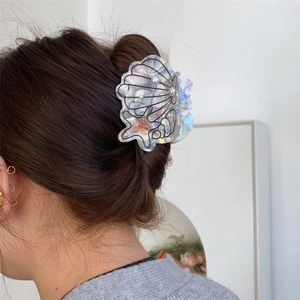 Detail of seashell and starfish hair claw with pearls worn on hair from a side view