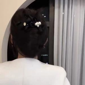Elegant black satin bow hair clip with white pearls and gold charm on female model hair