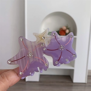 Detail of starfish hair claw clip with purple acetate base and sparkling rhinestones