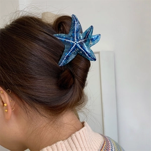 Détail de la pince à cheveux étoile de mer bleue avec des pois blancs sur un chignon