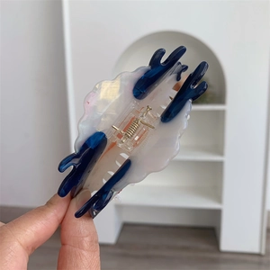 Detail view of the large acetate shark hair claw clip in blue and pearly white finish