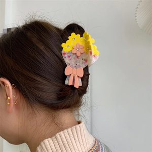 Dettaglio della grande molletta per capelli a fiore in acetato con strass indossata