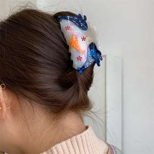 Detail showing dolphin pattern claw clip with pearl-like finish on model hairstyle