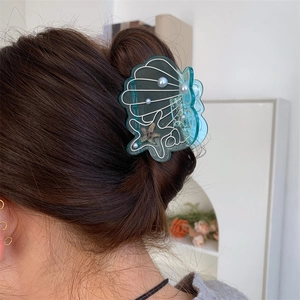 Blue shell hair claw with pearl and starfish accent shown from back view on hair