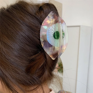 Détail de la pince à cheveux en acétate avec fleur de camélia et gemme verte