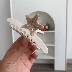 Dettaglio di un fermaglio per capelli a stella marina in acetato bianco e marrone