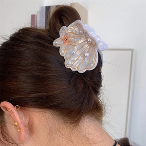 Elegant white seashell hair claw clip with pearls and star accent on brunette hair