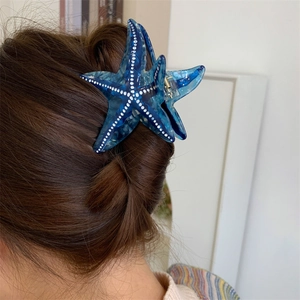 Vue détaillée d'une pince à cheveux étoile de mer en acétate bleu avec des points blancs