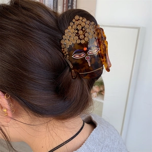 Détail d'une pince à cheveux en acétate avec design tête de bouddha et motif tortue