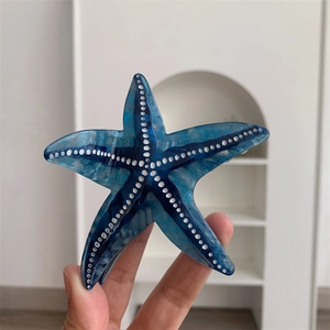 Détail de la pince à cheveux étoile de mer au motif marbré bleu et points texturés blancs