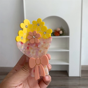 Dettaglio del fermaglio per capelli francese in acetato con fiori e strass tenuto in mano