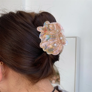 Detailed view of the seashell acetate hair claw with pearls worn on a model's hair