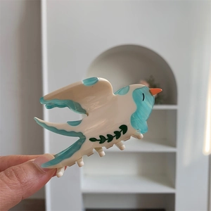 Détail de la pince à cheveux hirondelle en acétate avec motif marbré bleu et blanc élégant