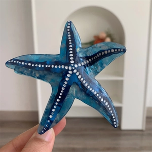 Détail de la pince à cheveux étoile de mer en acétate avec dégradé bleu et pois