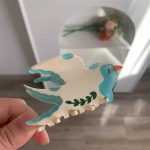 Détail d'une pince à cheveux en forme d'hirondelle avec motif marbré bleu en acétate