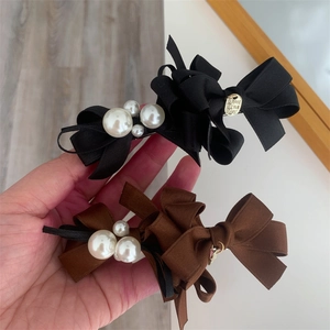 Detail of layered ribbon bow hair clips with white pearls and gold love charms