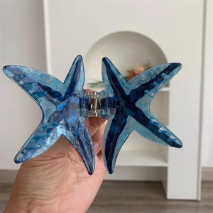 Détail d'une pince à cheveux étoile de mer montrant la texture acétate bleue et le ressort