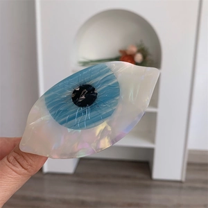 Vue détaillée de la pince à cheveux en acétate en forme d'œil aux reflets nacrés bleus