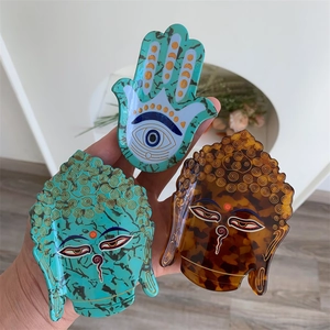 Détail des pinces à cheveux Main de Fatma et Bouddha en acétate vert et marron poli
