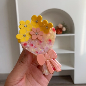 Dettaglio della molletta per capelli floreale con fiori gialli e rosa e strass lucidi