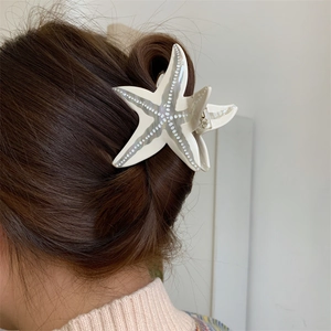 Vue détaillée de la pince à cheveux étoile de mer avec perles sur cheveux bruns