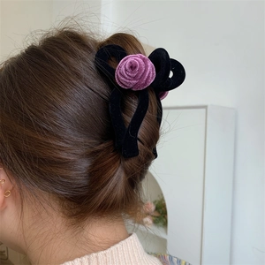 Detailed view of an elegant purple velvet rose and black bow hair claw on long hair