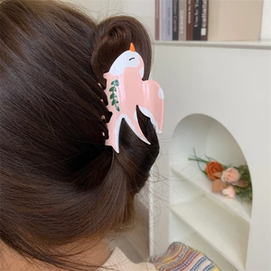 Pince à cheveux hirondelle rose et orange avec détail de feuille sur chignon brun