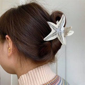 Détail d'une pince à cheveux étoile de mer avec points en relief sur une coiffure élégante