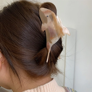 Detailed view of an acetate shark-shaped hair claw clip with marble texture on long hair