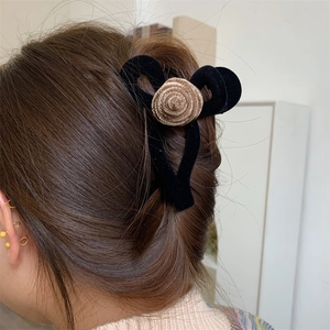 Close-up of velvet floral hair claw clip on brown hair with elegant black bow and flower
