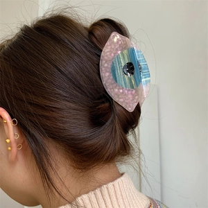 Vue détaillée d'une pince à cheveux en acétate en forme d'œil sur un chignon brun