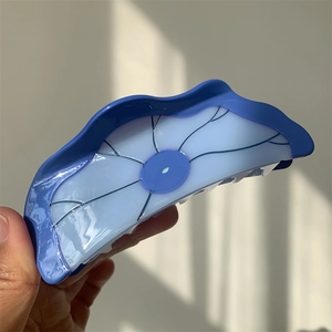 Vue détaillée d'une grande pince à cheveux en acétate en forme de lotus bleu dégradé