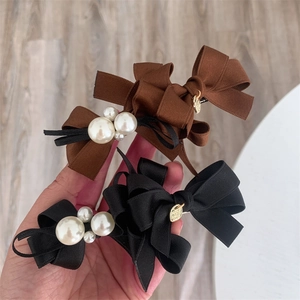 Detailed close-up of ribbon bow hair clips with faux pearls and gold heart charms